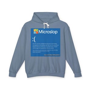 May include: A pale blue hoodie with a large blue graphic. The graphic displays the text "Microslop", a sad face, and a humorous error message. The Etsy shop URL is also included on the graphic.