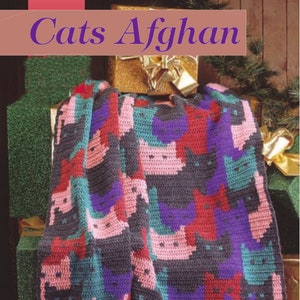 May include: A crocheted blanket with a pattern of cats in pink, red, purple, and teal on a gray background. The blanket has a fringe border.