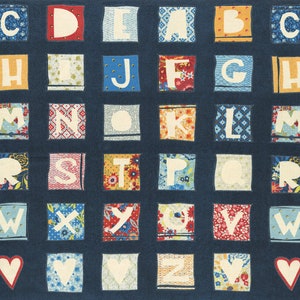 May include: A blue fabric alphabet chart with white letters on colourful patterned squares. The letters are arranged in alphabetical order and are surrounded by a white border. The chart is decorated with two white hearts.