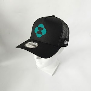 May include: Black baseball cap with a teal four-petal flower design on the front. The cap has a mesh back and a curved brim. The New Era logo is visible on the side.