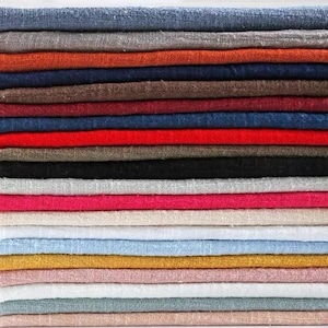 May include: A stack of folded fabric pieces in a variety of solid colors including blue, gray, orange, brown, red, black, white, pink, beige, yellow, and light green. Each piece of fabric features a visible woven texture with a loose, open weave.