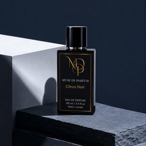 K&ouml;nnte beinhalten: Eine schwarze, rechteckige Parf&uuml;mflasche mit schwarzem Verschluss. Auf dem Etikett steht "MUSE DE PARFUM Citrus Noir EAU DE PARFUM 100 ml / 3.4 fl oz. Made in canada." Die Flasche steht vor dunklem Hintergrund.