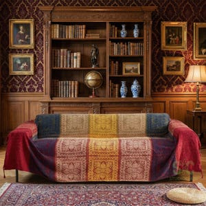 Pode incluir: Uma manta de sofá multicolorida com um design de patchwork. A manta apresenta quadrados azuis, bege, amarelos e vermelhos com um padrão floral. Está colocada sobre um sofá preto numa sala com uma estante de madeira e decoração antiga.