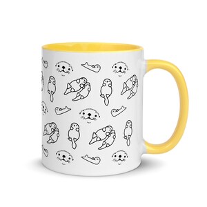 May include: White ceramic mug with a yellow interior and handle. The mug features a repeating pattern of black line-drawn otters in different poses. The otters are swimming, floating, and cuddling. A fun, whimsical design.