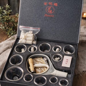 May include: A gray box set containing cupping therapy tools. The set includes clear cups, a pump, and other accessories. The box lid has Chinese characters and the brand name "HUA TO".