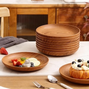 Puede incluir: Platos de madera con un patrón de vetas naturales. Un plato está lleno de fruta fresca, incluyendo fresas, arándanos y fruta del dragón. Se ven un tenedor y una cuchara.