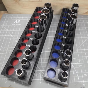 May include: Two black socket organisers with red and blue inserts, holding various chrome sockets. The organisers are labelled with sizes and numbers. The background is a grey cutting mat, A3 size (45 x 30 cm).