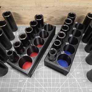 May include: Two black socket organizers with various sized sockets. The organizers have red and blue felt bottoms. Sockets are labeled with sizes like 1 1/16 and 15/16.