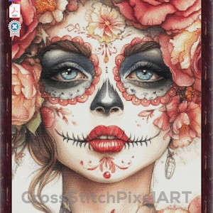 May include: A framed cross-stitch portrait of a woman with sugar skull makeup, decorated with red roses and floral accents. The woman has blue eyes, red lips, and a black nose. The artwork is framed in a dark brown wooden frame.