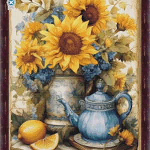 Op de afbeelding: Kruissteekpatroon met een stilleven met zonnebloemen, blauwe hortensia's en een blauwe theepot. Een citroen en een schijfje citroen liggen op een tafel. De tekst "CrossStitchPixelART" staat onderaan.