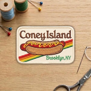 May include: Embroidered patch featuring a Coney Island hot dog with mustard, set against a rainbow stripe. The patch reads "Coney Island" in brown script and "Brooklyn, NY" in green.