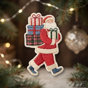 May include: An embroidered patch featuring Santa Claus wearing a red suit with white trim and blue boots. Santa is walking while carrying a stack of three wrapped gift boxes in red, blue, and green plaid patterns, plus one in his arm.