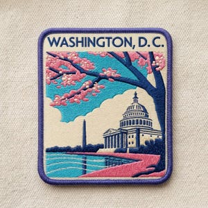 May include: A rectangular embroidered patch with a purple border featuring the text WASHINGTON, D. C. at the top. The design depicts the U.S. Capitol building, the Washington Monument, and a cherry blossom tree with pink flowers against a blue sky.