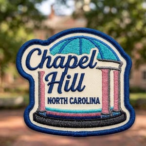 May include: An embroidered patch featuring a blue border and a cream-colored background. It depicts a stylized dome structure with pink columns and blue accents. The text reads Chapel Hill in blue script and NORTH CAROLINA in blue block letters.