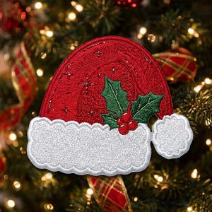 May include: An embroidered patch shaped like a red Santa hat with a white fluffy brim and a white pom-pom. The red fabric features stitched star details and a central green holly leaf design with three small red berries attached to the side.