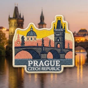 May include: An embroidered patch featuring a stylized depiction of the Charles Bridge in Prague, Czech Republic. The design includes a dark gray bridge with arches, a dome, and a tower against a yellow and peach sky. The text reads PRAGUE CZECH REPUBLIC.