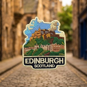 May include: An embroidered patch featuring a detailed landscape of Edinburgh Castle atop a hill with green slopes and stone buildings under a blue sky. The bottom section is a dark blue rectangle with the white text EDINBURGH SCOTLAND.