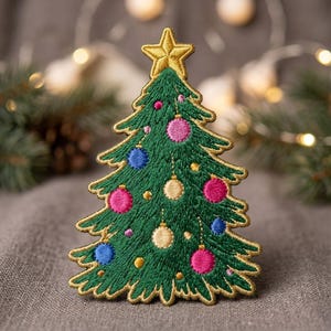 May include: An embroidered patch shaped like a Christmas tree in dark green thread with a gold star at the top. The tree is decorated with small, circular ornaments in shades of pink, blue, and gold, all outlined with a metallic gold thread border.
