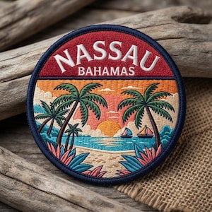 May include: A circular embroidered patch featuring a red upper section with the white text NASSAU BAHAMAS. The lower section depicts a tropical beach scene with palm trees, a sunset, two sailboats on blue water, and colorful foliage.