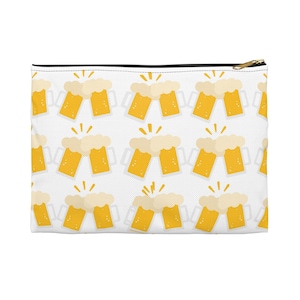 Może przedstawiać: Biała kosmetyczka zapinana na zamek z powtarzającym się wzorem kreskówkowych kufli do piwa. Każdy kufel wypełniony jest złotym piwem i zwieńczony białą pianą. Projekt zawiera żółte akcenty i zamek błyskawiczny jest złoty.