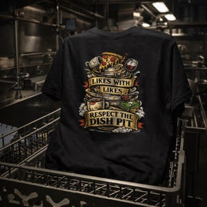 May include: Black t-shirt featuring a graphic of stacked plates, pizza, and a wine glass. The design includes the text "LIKES WITH LIKES" and "RESPECT THE DISH PIT" on banners. The shirt is displayed in a commercial kitchen setting.