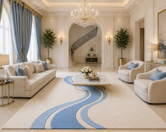 May include: A rectangular area rug featuring a cream-colored base with a prominent, flowing wave pattern in shades of blue. The rug is positioned in a living room with cream sofas, armchairs, blue curtains, and a marble-topped coffee table.