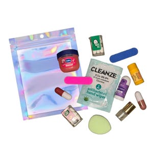 May include: A collection of small personal care items, including a pink lip balm, a small jar of Vaseline, a nail file, and a packet of antibacterial hand wipes. A clear iridescent pouch is also included.