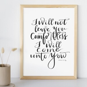 以下が含まれることがあります： 手書きのテキスト「I will not leave you comfortless, I will come unto you」が黒い筆記体で書かれた額入りのプリント。フレームは明るい木材で、プリントは白い紙に印刷されています。ベージュの花瓶とドライフラワーが左側にあります。