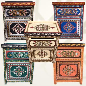 May include: A collection of hand-painted wooden bedside tables. Each table features intricate floral and geometric designs in various colors, including black, blue, green, and orange. The tables have drawers and decorative borders, showcasing a blend of artistry and functionality.