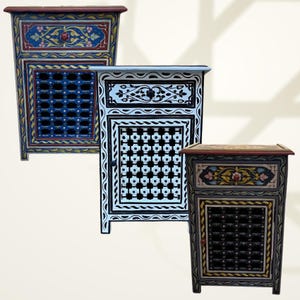 May include: Three decorative wooden side tables with intricate hand-painted designs. The tables feature floral and geometric patterns in various colors, including blue, white, and black. Each table has a unique design on the front and top.