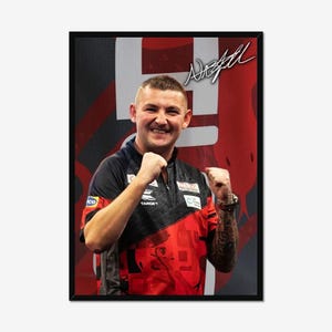 May include: Framed portrait of a smiling man in a red and black sports jersey, with the word "TARGET" visible. The background is red with white accents. The man has a tattoo on his arm and a signature in the top right corner.