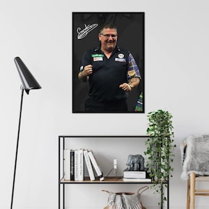 May include: A framed print featuring a smiling man in a black polo shirt with patches and a plaid sleeve. The background is dark gray, and there is a white signature in the upper left corner. The print is displayed on a white wall.