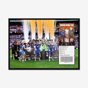 May include: A framed image of a football team celebrating a win, with confetti and a trophy. The image includes a ticket with the text "FINAL" and "VANARAMA NATIONAL LEAGUE". The team is wearing blue and white uniforms.