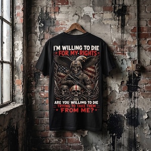 May include: A black t-shirt featuring a graphic print of a skull wearing a military helmet, a bald eagle, and an American flag. The text reads: I'M WILLING TO DIE FOR MY RIGHTS. ARE YOU WILLING TO DIE TRYING TO TAKE THEM FROM ME? The design includes chains.