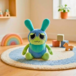 Puede incluir: Un peluche de conejo azul y verde con una expresi&oacute;n triste. El juguete tiene orejas largas y est&aacute; sentado sobre una alfombra azul y blanca. Un arco&iacute;ris de madera y bloques de construcci&oacute;n son visibles en el fondo, creando una escena l&uacute;dica.