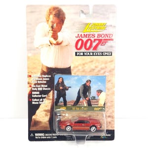 May include: A Johnny Lightning James Bond 007 "For Your Eyes Only" die-cast metal car. The red car is in its original packaging, featuring images of James Bond and the movie title. The packaging includes text about the car's features.
