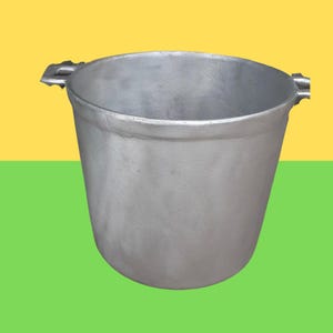 Könnte beinhalten: Ein silberfarbener Metalltopf mit einer weiten, offenen Oberseite und einem abgerundeten Boden. Der Topf verfügt über zwei kleine, stabile Griffe an den gegenüberliegenden Seiten des Randes. Die Außenfläche hat eine matte, texturierte Oberfläche.