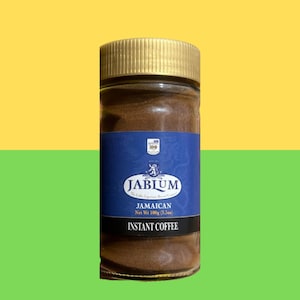 Puede incluir: Un frasco de vidrio de café instantáneo Jablum Jamaican con tapa dorada y etiqueta azul. La etiqueta presenta el nombre de la marca, un escudo y el texto "Jamaican Net Wt 100g (3.5oz) Instant Coffee."