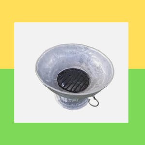 May include: A small, silver metal grill with a black grate. The grill has a bowl-like shape with a circular opening and a handle. It is designed for outdoor cooking and grilling, perfect for a barbecue.
