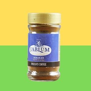 Op de afbeelding: Een glazen pot Jablum Jamaican instantkoffie met een gouden deksel en een blauw etiket. Het etiket toont de merknaam en de woorden "Jamaican Instant Coffee". Het nettogewicht is 56,7 g (2 oz), wat ongeveer 160 gram is.