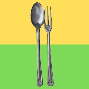 Może przedstawiać: Srebrny zestaw łyżki i widelca na żółto-zielonym tle. Łyżka ma zaokrągloną miseczkę, a widelec ma cztery zęby. Oba naczynia mają długie, smukłe uchwyty z ozdobnym detalem u podstawy.