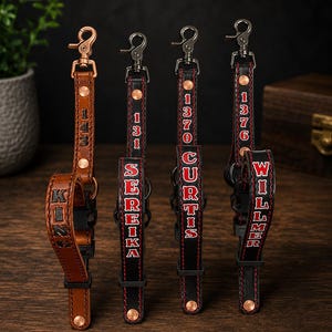 May include: Four leather straps with metal swivel clips and rivets. One is tan with the text KING and 143. Three are black with red stitching and red-outlined text reading SEREIKA, CURTIS, and WILLMER, each featuring numerical codes 131, 1370, and 1376.
