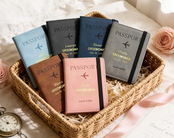 May include: A collection of personalized passport holders in various colors, including blue, gray, brown, and pink, arranged in a woven basket. Each holder is embossed with the word "PASSPORT" and a small airplane icon, with names and dates below.