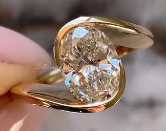 May include: A gold ring with a large, oval-cut diamond. The diamond is set in a unique, swirling design. The ring is held up, showcasing the sparkle of the diamond. The text "Billionaire Jewelry" is visible on the ring.