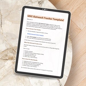 May include: A digital tablet displays a "UGC Outreach Tracker Template!" with instructions on how to use it. The template helps users stay organized when pitching to brands. The tablet is on a light-colored, patterned surface.