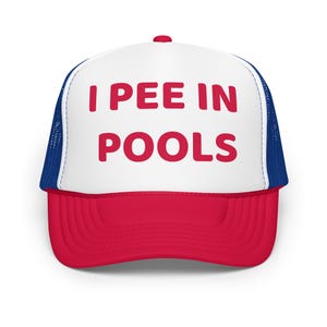 Può includere: Cappellino da camionista rosso, bianco e blu con la scritta "I PEE IN POOLS" a blocchi rossi. Il cappellino ha una visiera rossa, un pannello frontale bianco e un retro in rete blu.