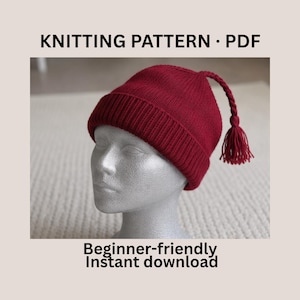 May include: A knitted red hat with a tassel, displayed on a mannequin head. The hat has a ribbed brim and a twisted cord that ends in a tassel. Text on the image reads "KNITTING PATTERN • PDF" and "Beginner-friendly Instant download".