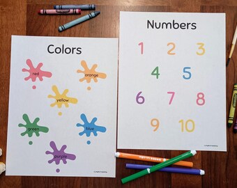 Puede incluir: Dos pósteres educativos sobre papel blanco. El póster de la izquierda titulado Colors presenta seis manchas de pintura en rojo, naranja, amarillo, verde, azul y morado con texto a juego. El póster de la derecha titulado Numbers muestra los números del uno al diez.