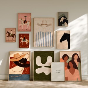 May include: A collection of framed art prints featuring equestrian and abstract themes. The prints showcase illustrations of cowboys, horses, and abstract shapes in a variety of colors, including pink, brown, and green. One print includes the text "let's stay in bed."