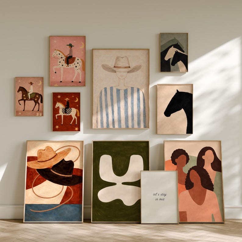 May include: A collection of framed art prints featuring equestrian and abstract themes. The prints showcase illustrations of cowboys, horses, and abstract shapes in a variety of colors, including pink, brown, and green. One print includes the text "let's stay in bed."